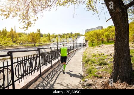 Homme à barbe grise en marche près de la rivière dans le parc de la ville au matin. Concept de vie sain Banque D'Images