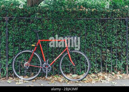 Londres/UK-30/7/18 : le vélo rouge est enchaîné à la clôture sur le côté d'une rue à Londres Banque D'Images