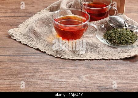 Tasses de thé en verre avec serviette en napkin de Hesse sur fond en bois Banque D'Images