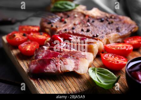 Bifteck grillé avec tomates et basilic à bord de coupe, gros plan Banque D'Images