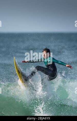 Un jeune adolescent en action de surf à Fistral à Newquay, dans les Cornouailles. Banque D'Images