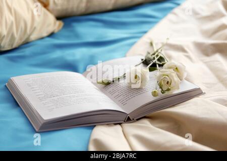 Livre ouvert et belle fleur sur un lit froissé Banque D'Images