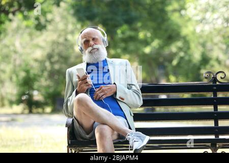 Homme âgé écoutant de la musique dans un parc Banque D'Images