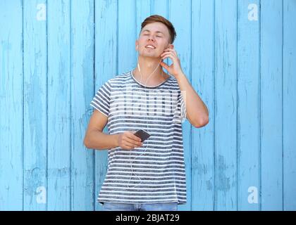 Un homme sympathique qui écoute de la musique sur fond de bois Banque D'Images