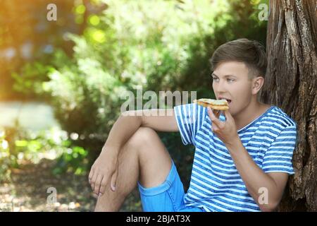 Un sympathique gars qui mange de la pizza sur l'herbe Banque D'Images