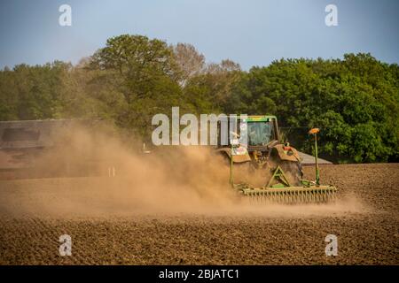 Agriculteur travaillant dans les champs au printemps, sec en avril 2020, le tracteur tire un épais nuage de poussière, tout en cultivant, en desserrant le sol, derrière lui, Niederrhein Banque D'Images