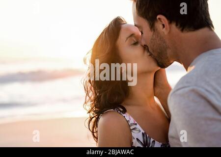 Un jeune couple affectueux qui s'embrasse sur une plage au crépuscule Banque D'Images