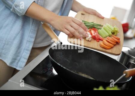 Femme mains mettre des légumes dans la poêle se rapprochep Banque D'Images