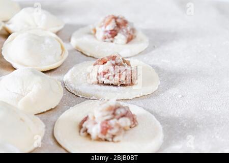 Le processus de fabrication de boulettes maison. Viande hachée sur la pâte, le processus de fabrication de boulettes maison. Cuisine russe. Banque D'Images