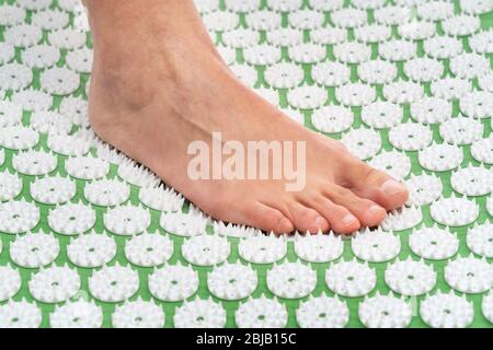 Pied féminin sur un tapis d'acupuncture. Acupuncture, massage. Médecine alternative. Banque D'Images