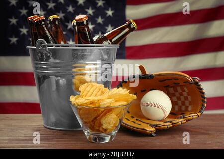 Gant de baseball avec balle, chips et bière sur table en bois Banque D'Images