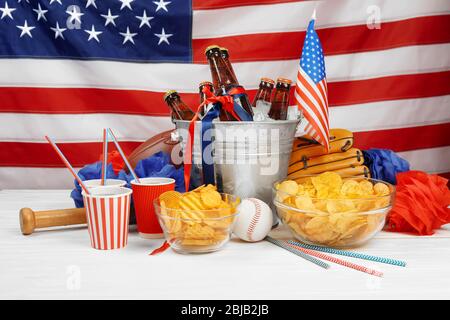 Seau avec bouteilles de bière, chips et équipement de sport sur table en bois blanc Banque D'Images