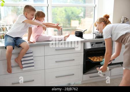 Dégustation de biscuits pour la jeune mère et les enfants dans la cuisine Banque D'Images