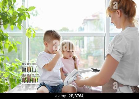 Dégustation de biscuits pour la jeune mère et les enfants dans la cuisine Banque D'Images