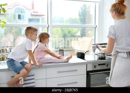 Dégustation de biscuits pour la jeune mère et les enfants dans la cuisine Banque D'Images