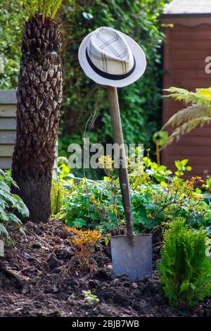 Un chapeau de paille accroché sur l'arbre en bois et la poignée d'une cosse de jardin traditionnelle avec un arbre en bois et une poignée. Banque D'Images