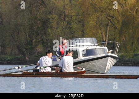 Deux hommes dans une arnaque regardant un bateau motorisé ils passent sur la rivière Severn à Shrewsbury Royaume-Uni Banque D'Images