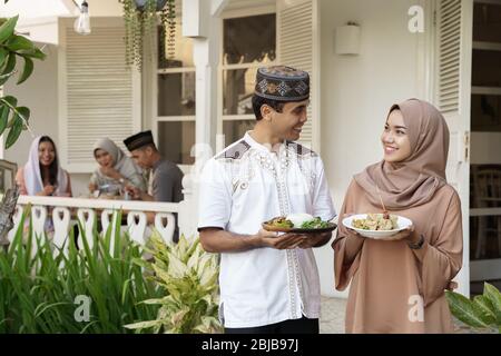 couple avec la nourriture servant leur ami au cours du dîner de ramadan iftar Banque D'Images