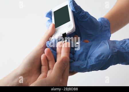 Médecin vérifiant le taux de sucre dans le sang par glucometer et test de bande à la maison Banque D'Images