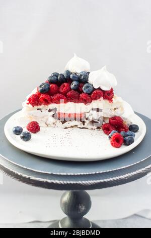 Tranche de gâteau de pavlova avec remplissage de baies, crème fouettée, baies fraîches. Fond blanc Uni. Espace de copie. Banque D'Images