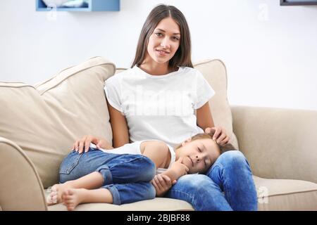 Jolie fille posée sur les genoux des mères à la maison Banque D'Images