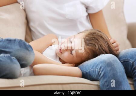 Jolie fille posée sur les genoux des mères à la maison Banque D'Images