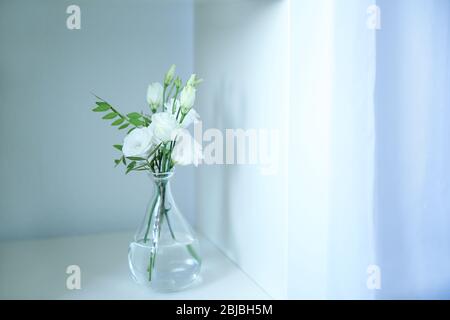 Belles fleurs d'eustoma dans un vase en verre sur une étagère blanche Banque D'Images