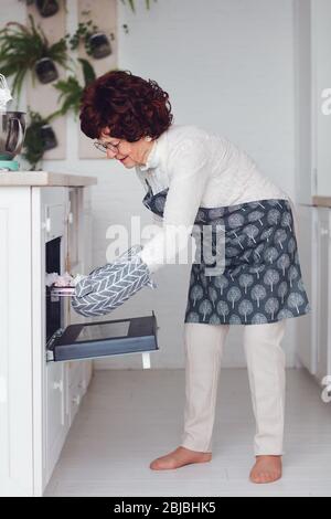 bonne grand-mère élégante cuisson sur la cuisine à la maison, les dernières préparations pour un dîner en famille Banque D'Images