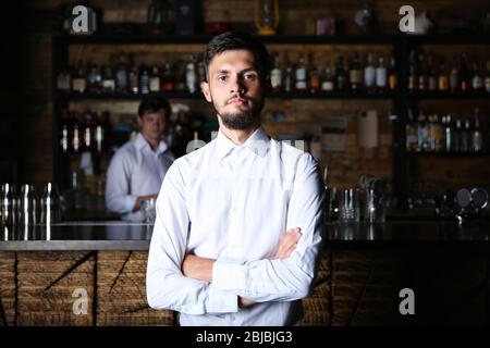 Homme en chemise blanche debout sur comptoir de bar en bois Banque D'Images