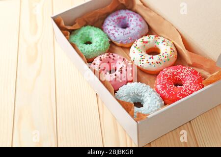 Beignets colorés dans une boîte sur fond en bois Banque D'Images