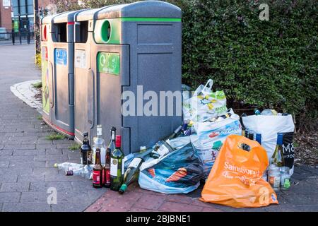 Sacs de bouteilles en verre à côté de poubelles de recyclage complètes, West Bridgford, Notinghamshire, Angleterre, Royaume-Uni Banque D'Images