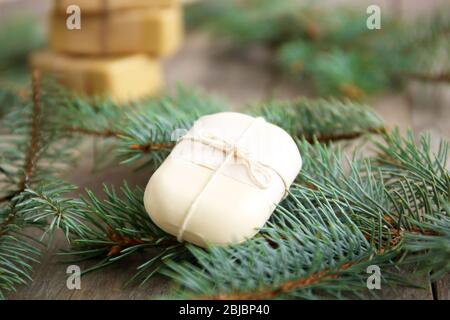 Morceau de savon de conifères et branches sur fond de bois, vue rapprochée Banque D'Images