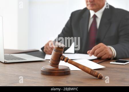 Un gavel brun sur une table en bois et un avocat masculin sur fond, vue rapprochée Banque D'Images