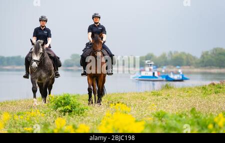 Bleckede, Allemagne. 29 avril 2020. Policewomen Yasmin Pröstler (l) et Anna Schloßer (r) font leurs chevaux de service le long des rives de l'Elbe lors d'une réunion de presse. Dans les semaines à venir, les officiers des escadrons équestres de Hanovre et Braunschweig doivent informer les visiteurs des règles de protection et punir les violations telles que le camping illégal et les feux ouverts. Crédit: Philipp Schulze/dpa/Alay Live News Banque D'Images