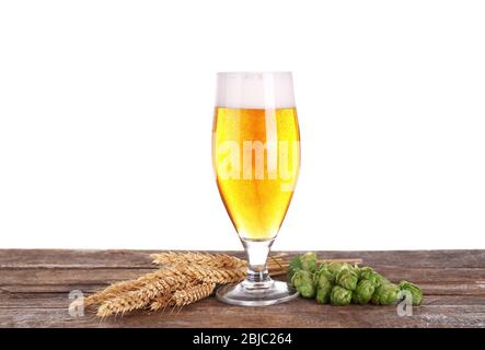 Verre de bière légère, spiquets de blé et cônes de houblon sur table en bois, isolé sur blanc Banque D'Images