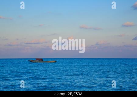 Belle vue d'un bateau dérivant dans l'eau bleue en toile de fond du ciel coloré au coucher du soleil (Havelock, île, Andaman, Inde) Banque D'Images