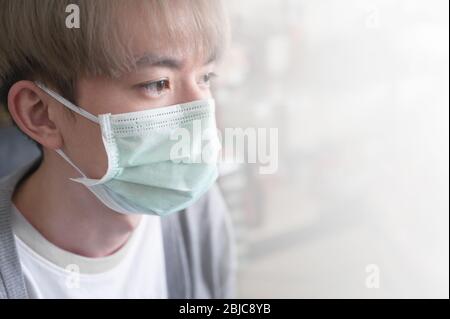 Jeune homme asiatique portant un masque médical sur fond blanc. Concept Coronavirus, pollution atmosphérique Banque D'Images