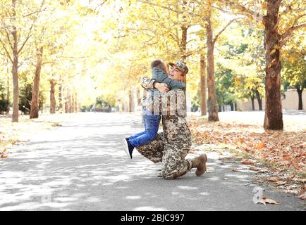 Mère soldat et petit enfant embrassant dans le parc Banque D'Images