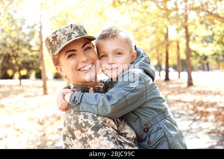 Mère soldat et petit enfant embrassant dans le parc Banque D'Images