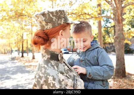 Mère soldat et petit enfant embrassant dans le parc Banque D'Images