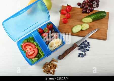 Lunchbox avec sandwich et fruits sur table en bois blanc Banque D'Images