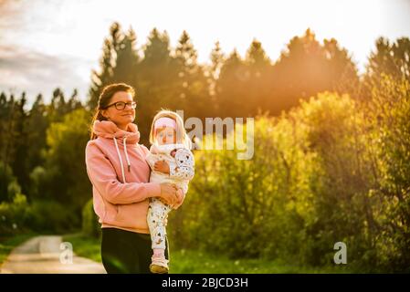 Mère et enfant marchant sur la route de campagne entre les champs agricoles vers le vilage de la forêt Banque D'Images