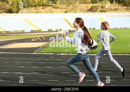 Des enfants sportifs qui courir sur la piste au stade Banque D'Images