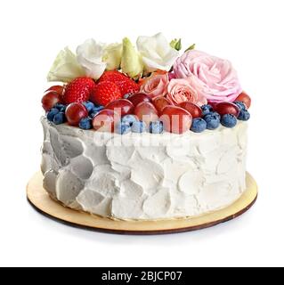 Délicieux gâteau décoré de baies et de fleurs sur fond blanc Banque D'Images