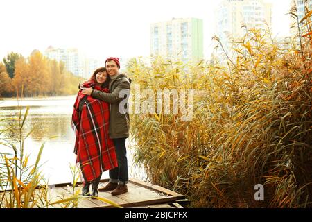 Beau couple jeune debout sur la jetée dans le parc d'automne Banque D'Images