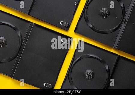 Ouvrez des DVD vides sur un fond jaune. Quatre boîtes en plastique pour disques compacts. Fond créatif multitâches. Vue de dessus. Gros plan. Banque D'Images