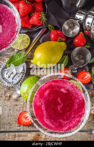 Boisson alcoolisée froide d'été. Cocktail de marguerite de fraise, avec citron vert, menthe et fraise fraîche sur fond rustique en bois Banque D'Images