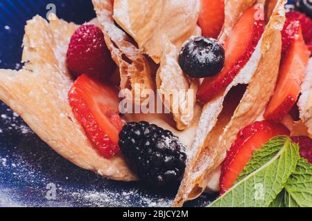 Le français dessert millefeuille de couches de pâte feuilletée avec la crème pâtissière, framboises, bleuets sur une plaque sur une table en béton, vue de dessus, fermer Banque D'Images