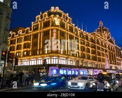 HARRODS NUIT NOËL SHOPPERS FLOU LA CIRCULATION Harrods grand magasin au crépuscule avec les lumières de Noël shoppers et passer le trafic flou Knightsbridge Londres SW1 Banque D'Images