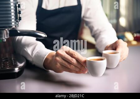 Barista masculin tenant deux tasses de café à la table Banque D'Images